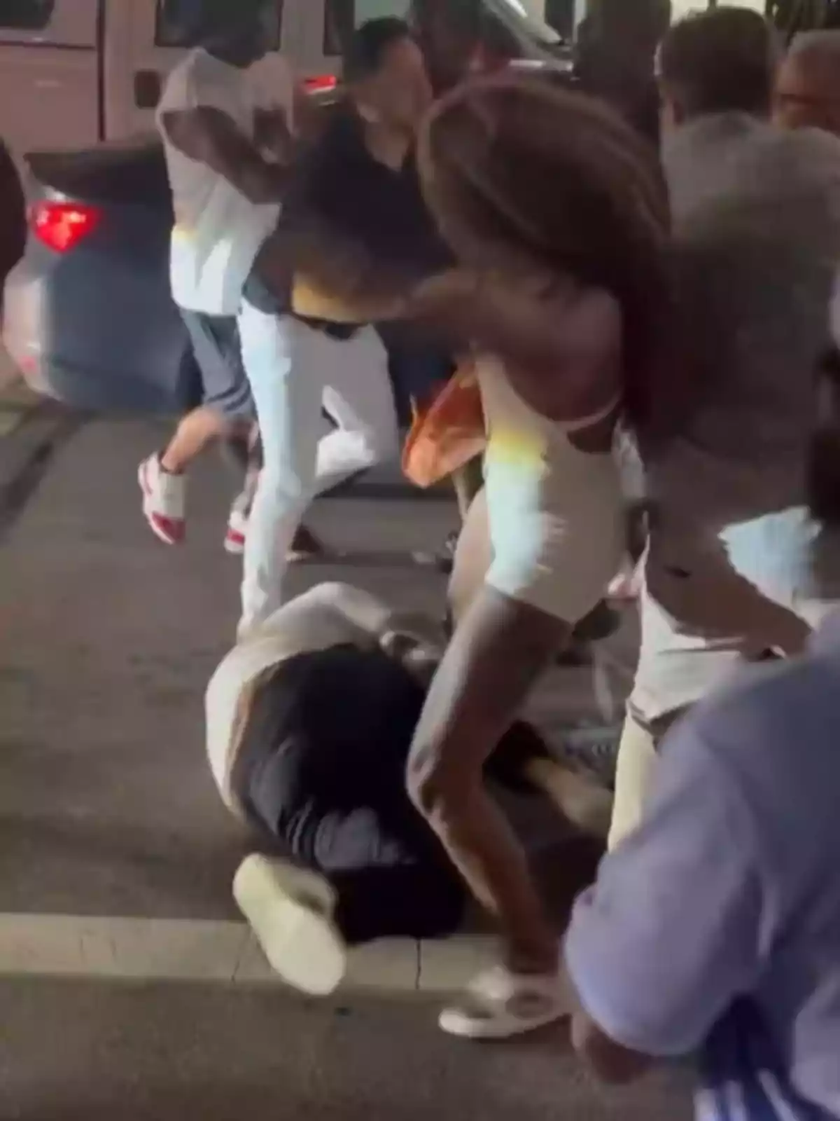 Varias personas involucradas en una pelea en la calle durante la noche, una persona está en el suelo mientras otras discuten y se empujan alrededor. Varias personas involucradas en una pelea en la calle durante la noche, una persona está en el suelo mientras otras discuten y se empujan alrededor.