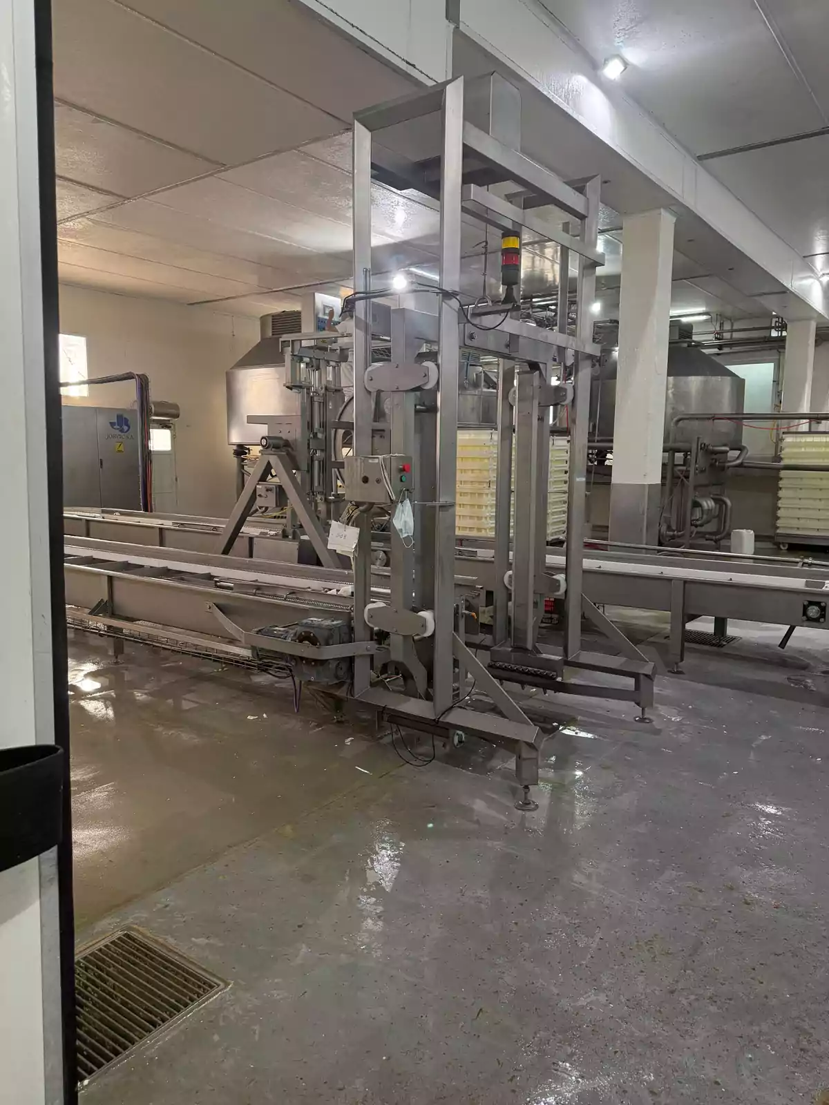 Máquina industrial de acero inoxidable en una planta de procesamiento de alimentos con piso mojado y ambiente limpio Máquina industrial de acero inoxidable en una planta de procesamiento de alimentos con piso mojado y ambiente limpio