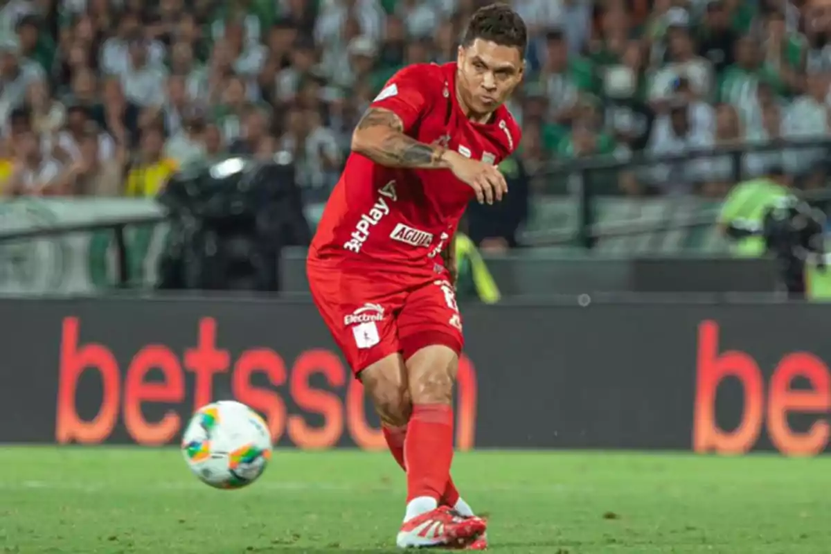 Soccer player in a red uniform kicking a ball during a match in a stadium full of spectators Soccer player in a red uniform kicking a ball during a match in a stadium full of spectators