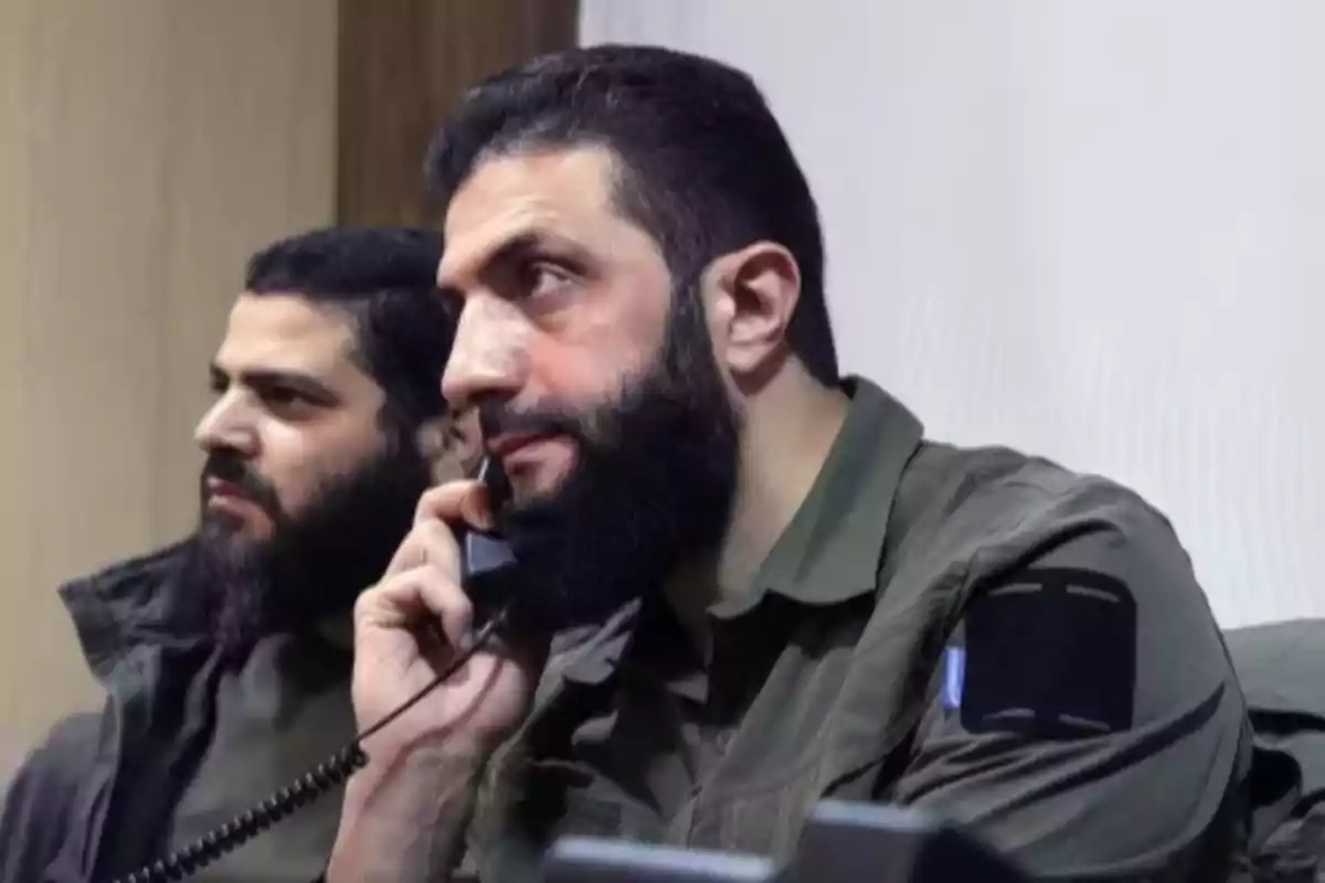 Dos hombres con barba y ropa militar, uno de ellos hablando por teléfono fijo.