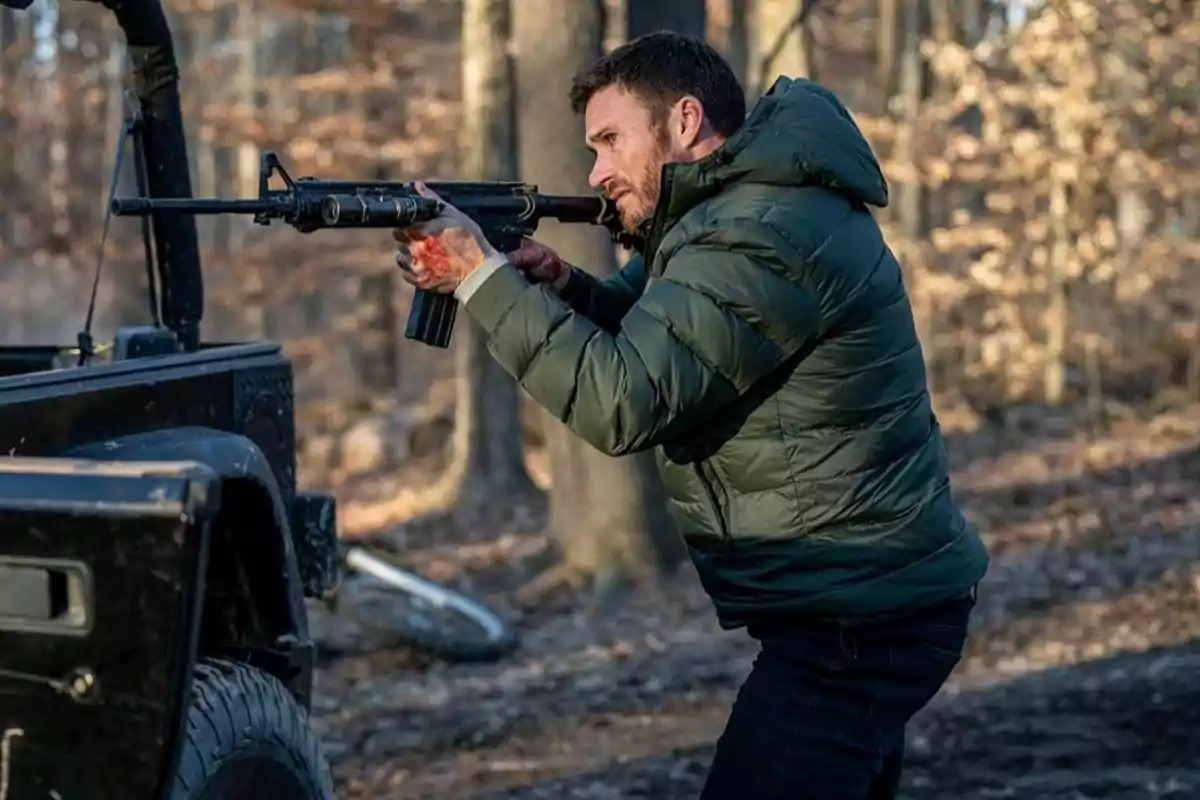 Man in a green jacket holding a rifle next to a vehicle in a forest Man in a green jacket holding a rifle next to a vehicle in a forest