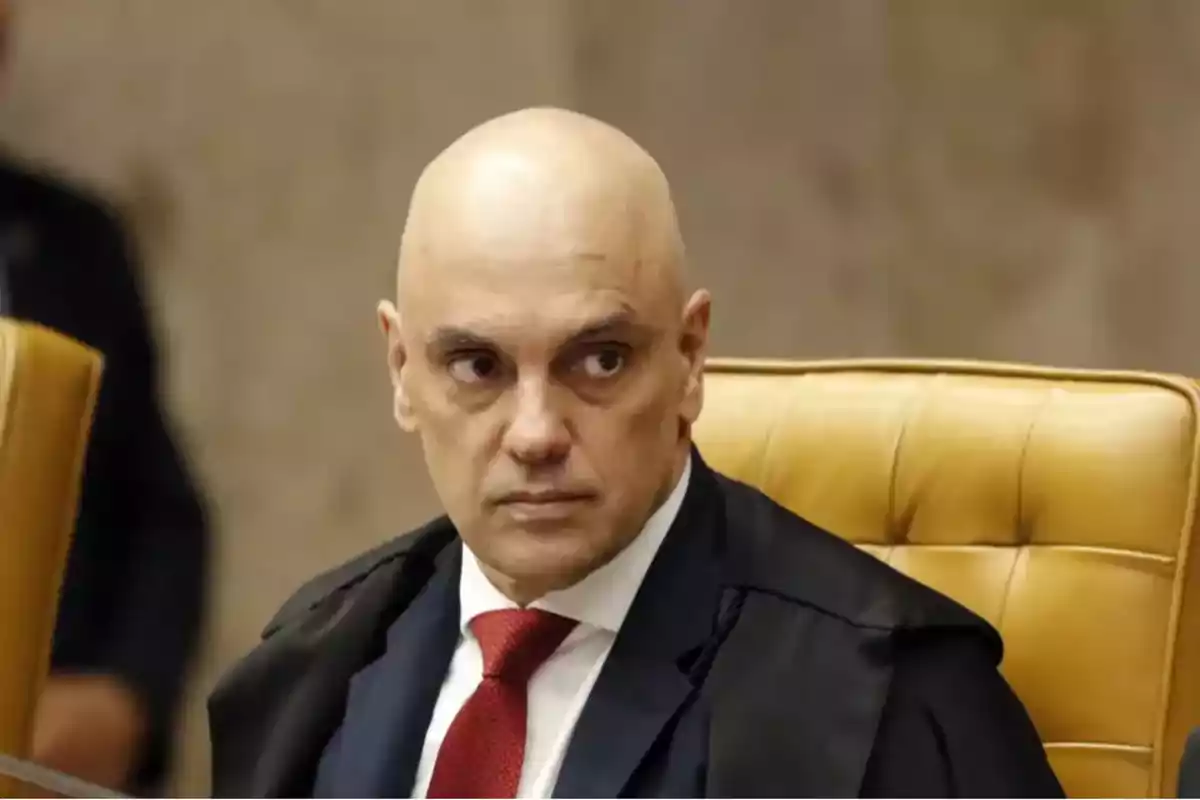 Bald man in a suit and red tie sitting on a yellow chair looking to the side Bald man in a suit and red tie sitting on a yellow chair looking to the side