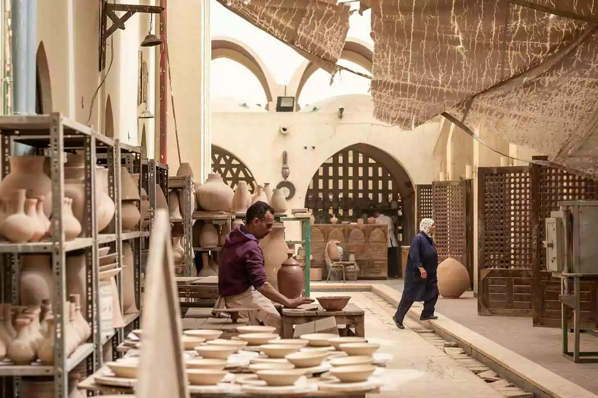 Ceramics workshop with shelves full of clay pots and people working in a traditional setting Ceramics workshop with shelves full of clay pots and people working in a traditional setting