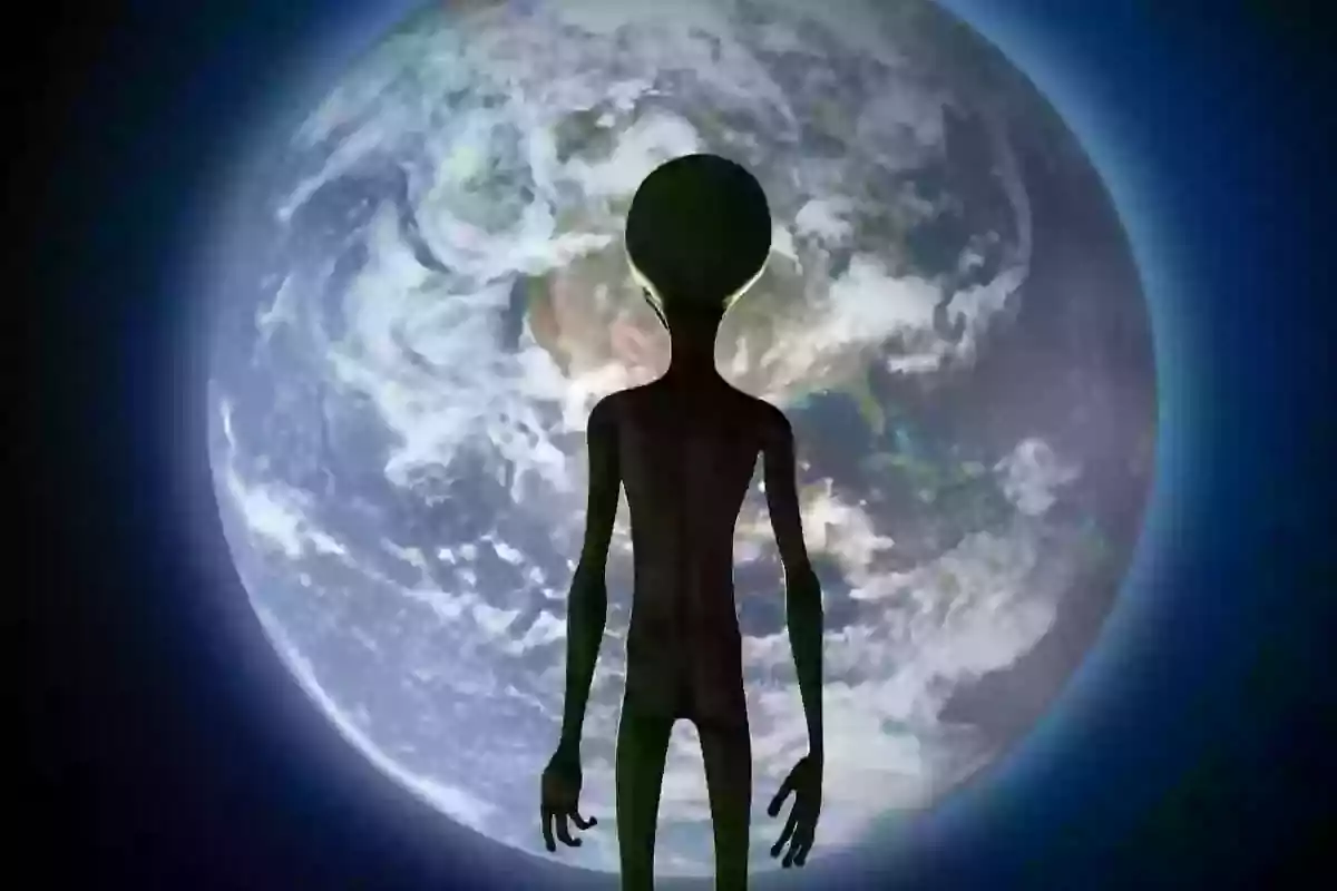 Un extraterrestre de silueta oscura está de pie frente al planeta Tierra visto desde el espacio Un extraterrestre de silueta oscura está de pie frente al planeta Tierra visto desde el espacio