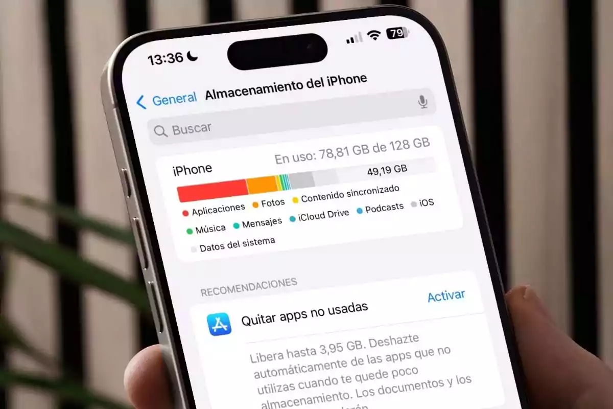Person holding an iPhone displaying the storage settings screen, showing space usage and recommendations to free up memory. Person holding an iPhone displaying the storage settings screen, showing space usage and recommendations to free up memory.