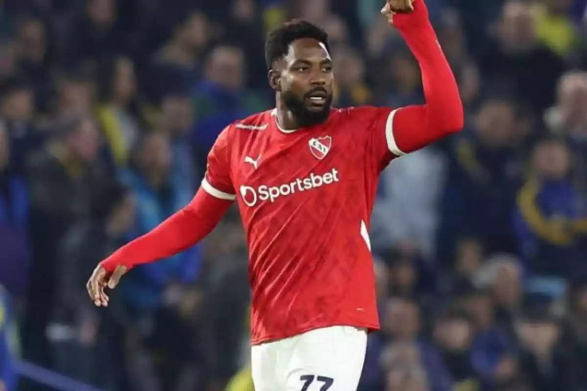 Soccer player in a red Independiente uniform celebrating in a stadium full of spectators Soccer player in a red Independiente uniform celebrating in a stadium full of spectators