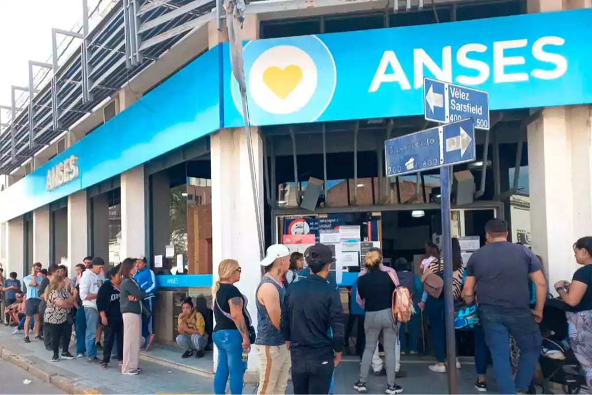 People standing in line at the entrance of an ANSES office on a city corner People standing in line at the entrance of an ANSES office on a city corner