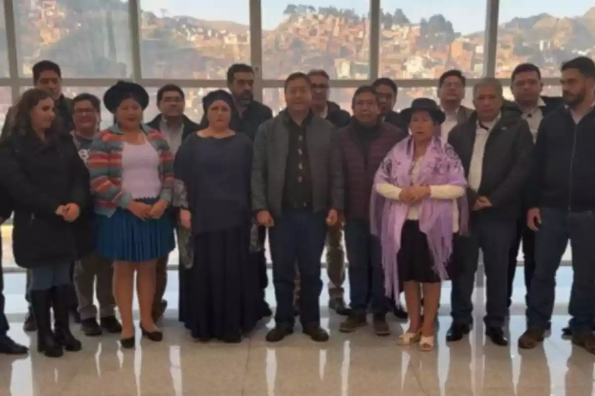 A group of people posing together in an indoor space with large windows and a city in the background A group of people posing together in an indoor space with large windows and a city in the background