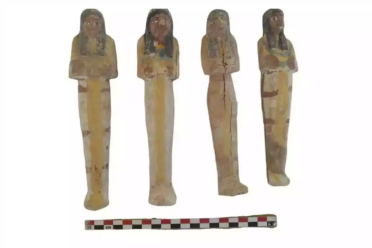 Four painted wooden Egyptian figures standing with crossed arms and a measuring scale at the bottom Four painted wooden Egyptian figures standing with crossed arms and a measuring scale at the bottom