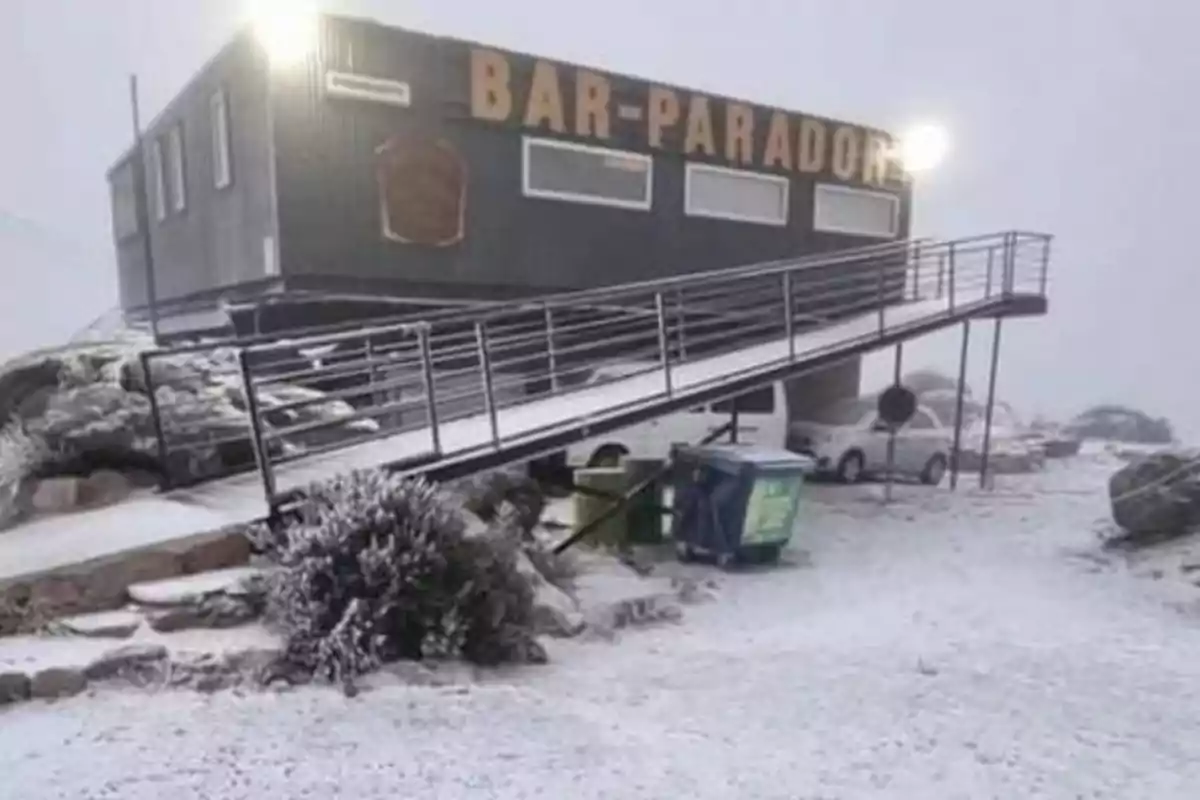 Bar in a snowy area with an access ramp and some cars parked in the background Bar in a snowy area with an access ramp and some cars parked in the background