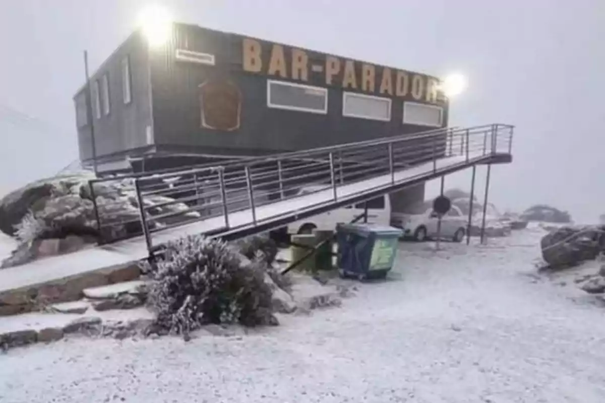 Bar Parador en una zona nevada con una rampa de acceso y algunos autos y contenedores al frente Bar Parador en una zona nevada con una rampa de acceso y algunos autos y contenedores al frente