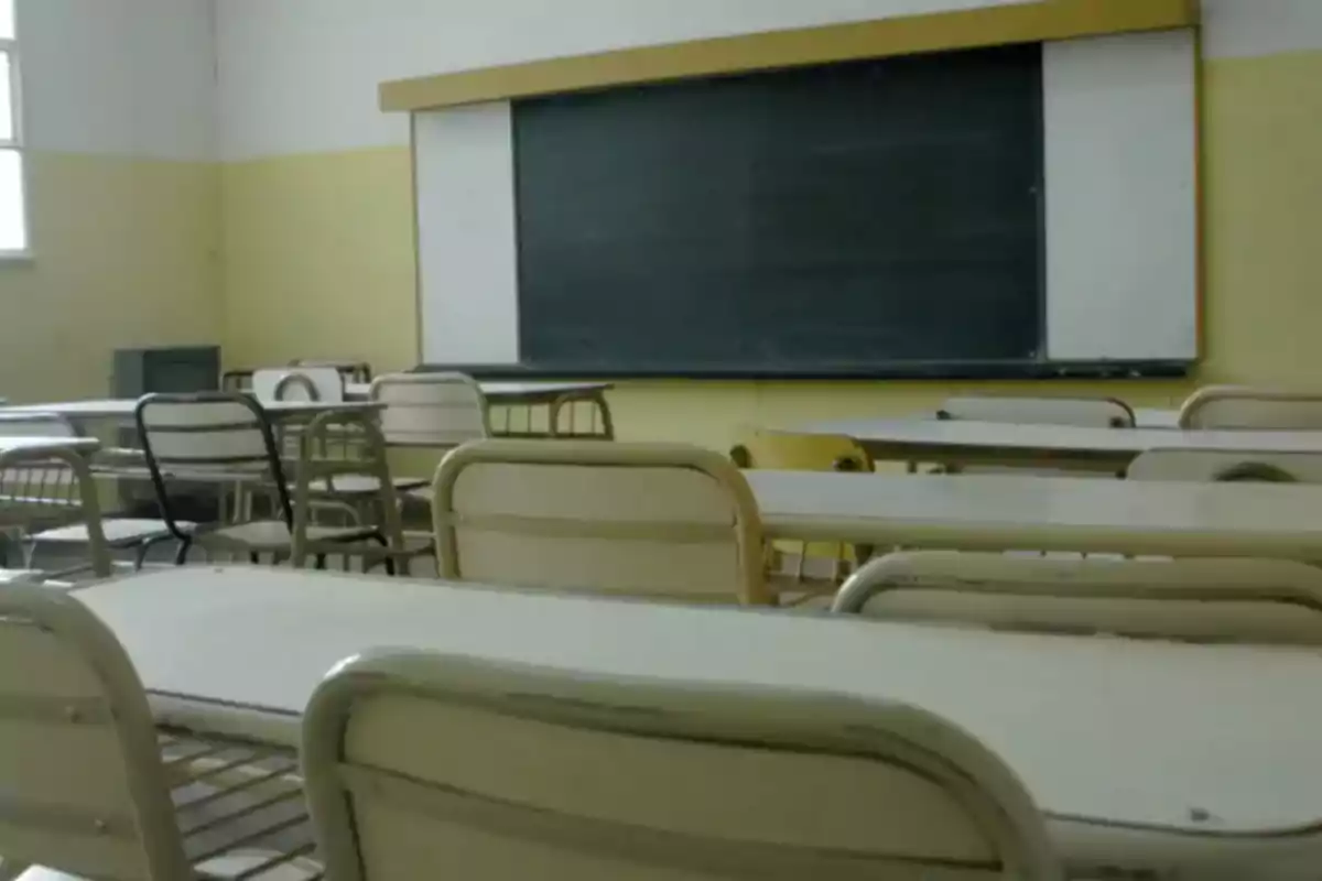 Aula vacía con pupitres y un pizarrón al fondo Aula vacía con pupitres y un pizarrón al fondo