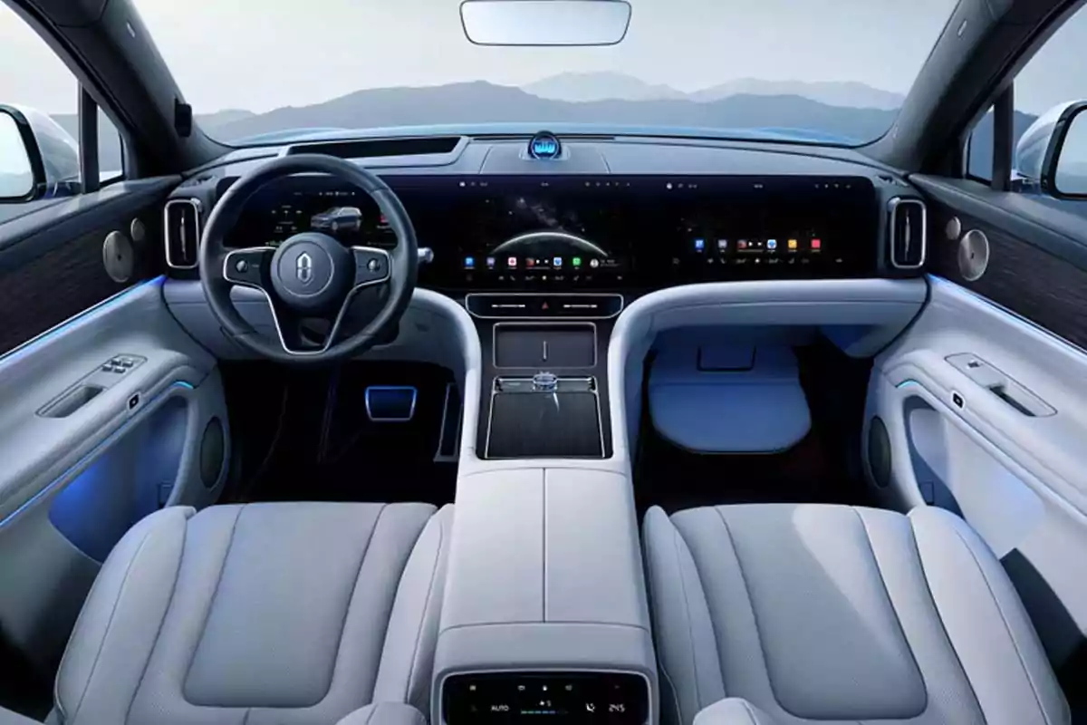 Interior moderno de un automóvil con asientos de cuero claro, volante multifunción y una gran pantalla digital que abarca todo el tablero, con detalles en madera y luces ambientales azules Interior moderno de un automóvil con asientos de cuero claro, volante multifunción y una gran pantalla digital que abarca todo el tablero, con detalles en madera y luces ambientales azules