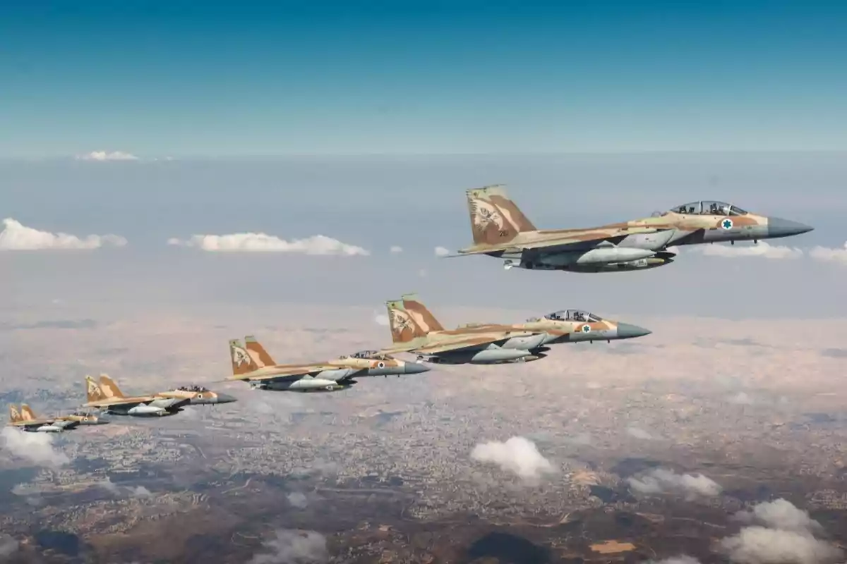 Five camouflaged fighter jets flying in formation over an arid landscape with a few scattered clouds Five camouflaged fighter jets flying in formation over an arid landscape with a few scattered clouds