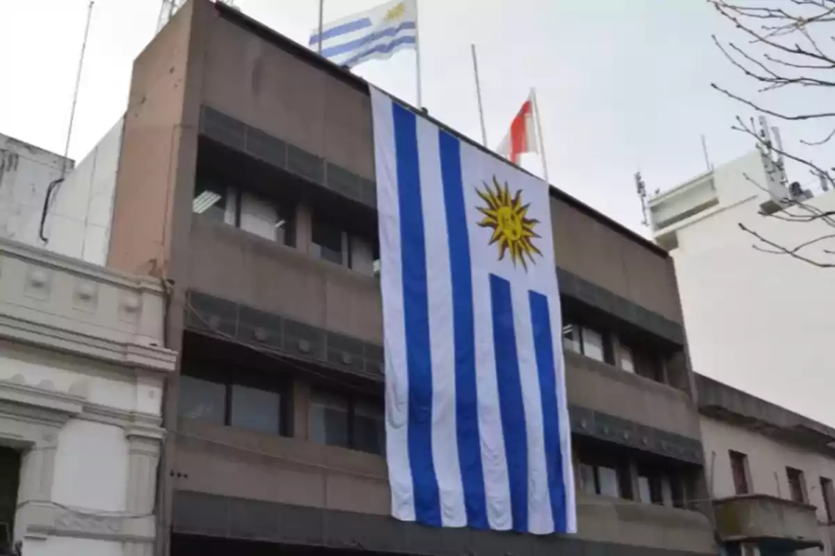 Building with a large Uruguayan flag hanging on the facade and other flags on the roof