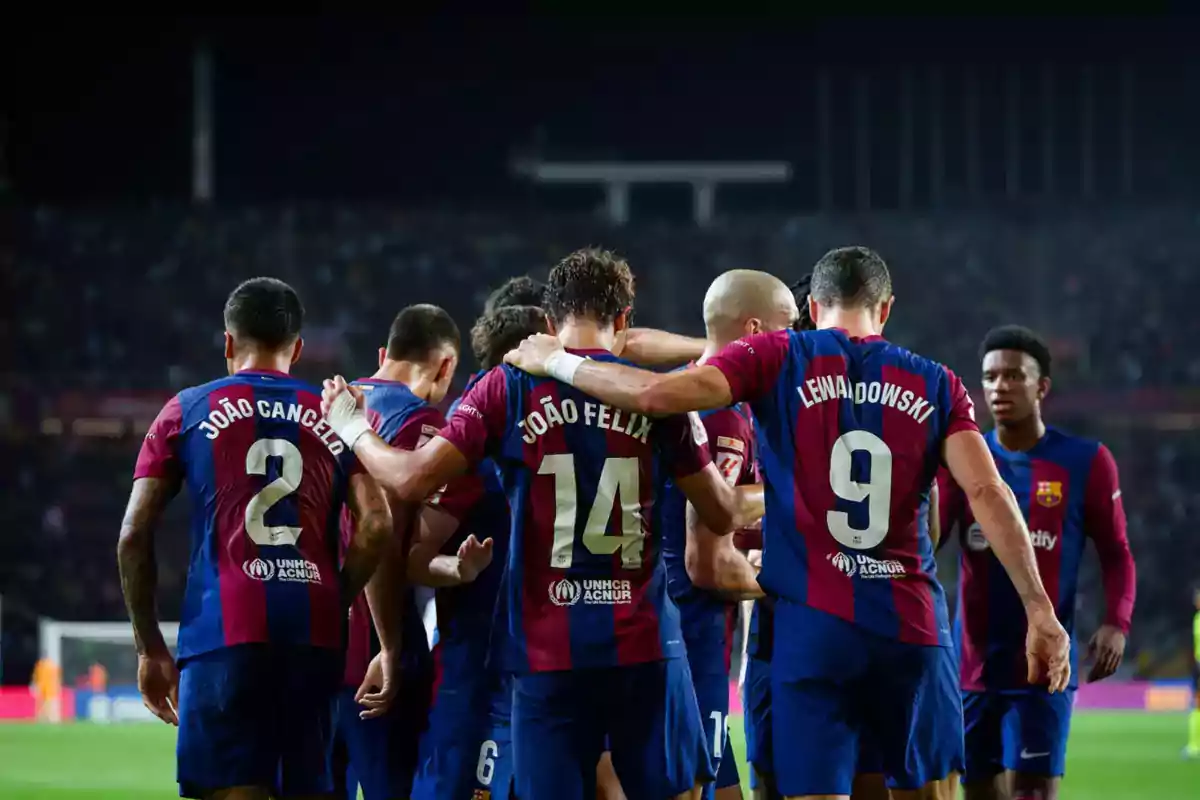 FC Barcelona players celebrate a goal together on the field during a night match.