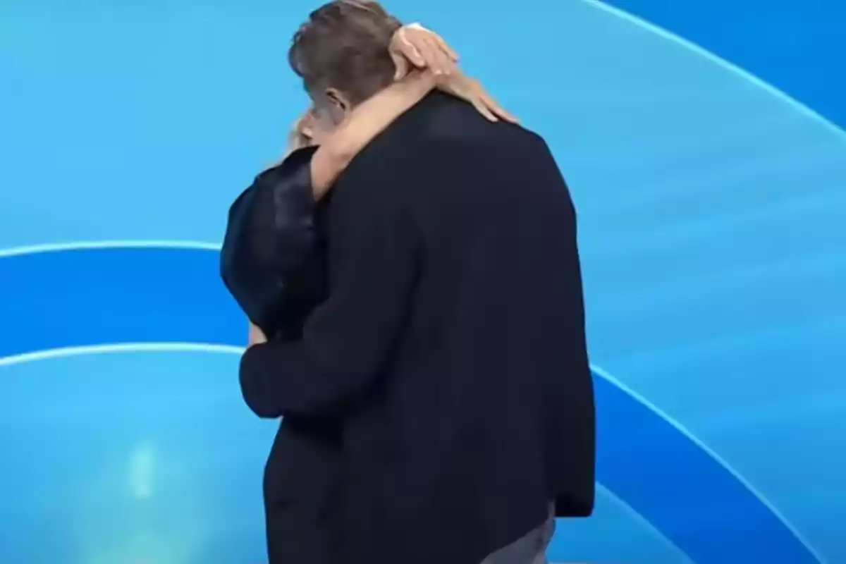 Dos personas se abrazan con fuerza sobre un fondo azul Dos personas se abrazan con fuerza sobre un fondo azul