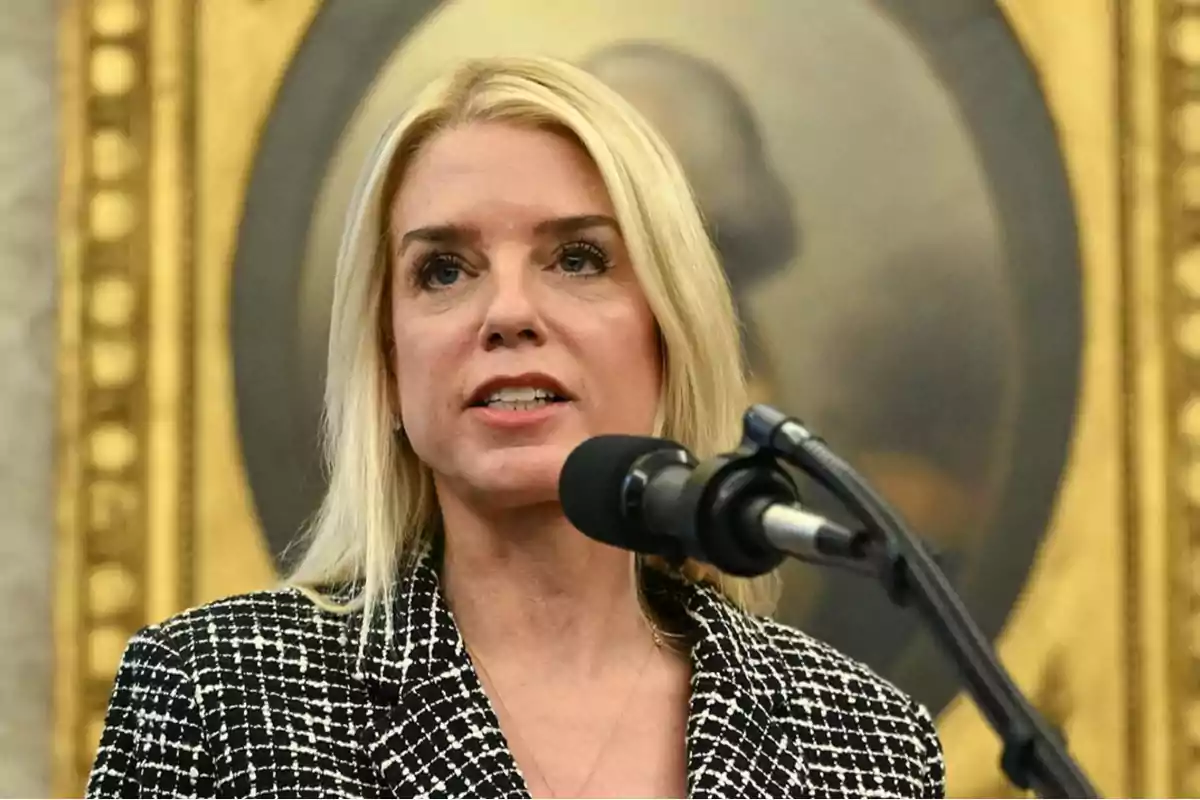 Blonde woman speaking in front of a microphone with a golden frame in the background Blonde woman speaking in front of a microphone with a golden frame in the background