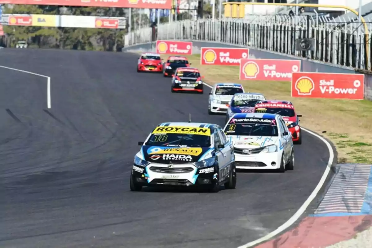 Varios autos de carrera compiten en una pista asfaltada durante una competencia automovilística