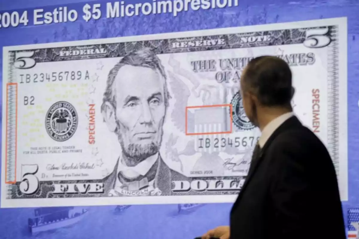 Hombre observando una proyección ampliada de un billete de cinco dólares estadounidenses con marcas de seguridad resaltadas