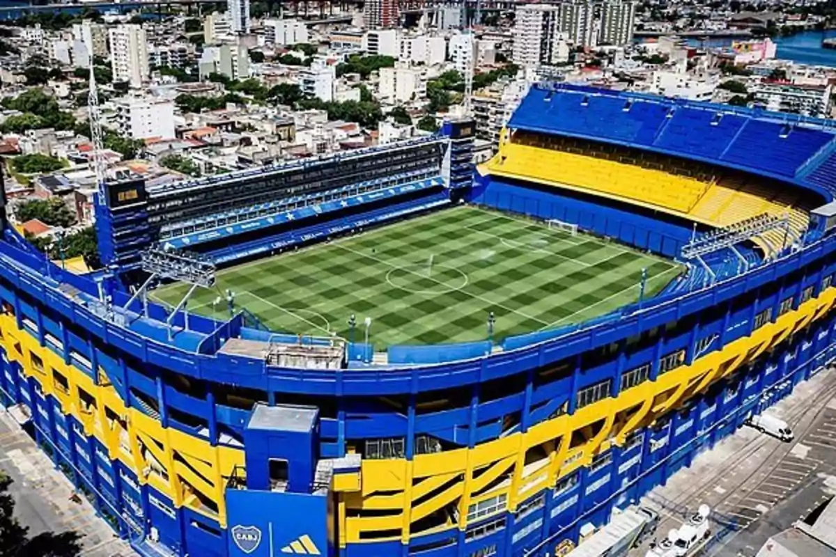 Aerial view of a blue and yellow painted soccer stadium surrounded by buildings in a city