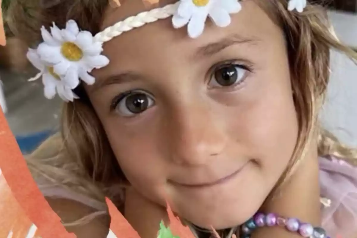 Niña con diadema de flores blancas y pulsera de cuentas de colores mirando a la cámara Niña con diadema de flores blancas y pulsera de cuentas de colores mirando a la cámara