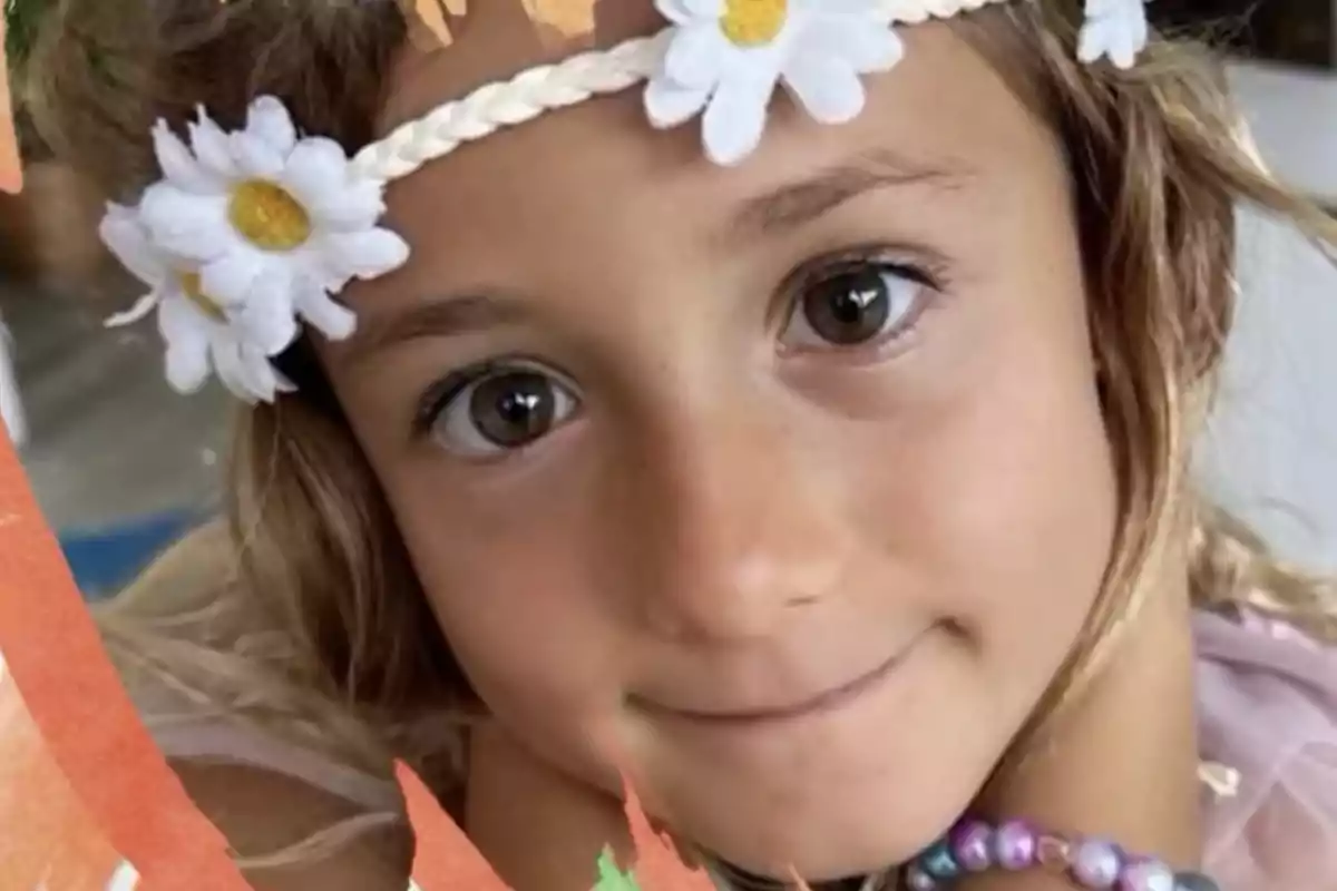 Niña con diadema de flores blancas y pulsera de cuentas de colores mirando a la cámara