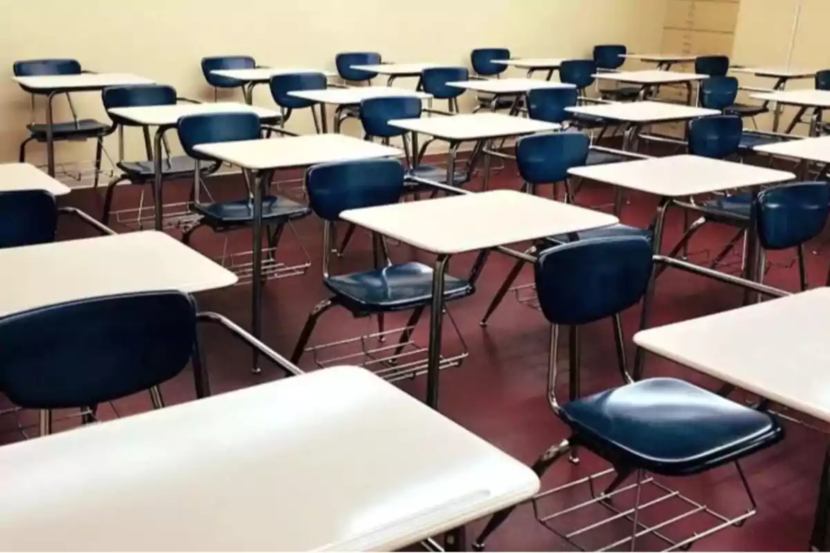 Empty classroom with blue desks and chairs arranged in rows on a red floor