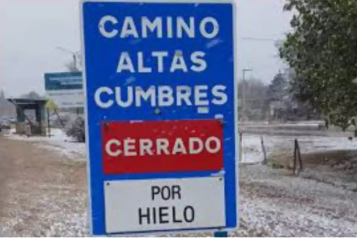 Cartel azul en la carretera que indica que el camino Altas Cumbres está cerrado por hielo con nieve alrededor