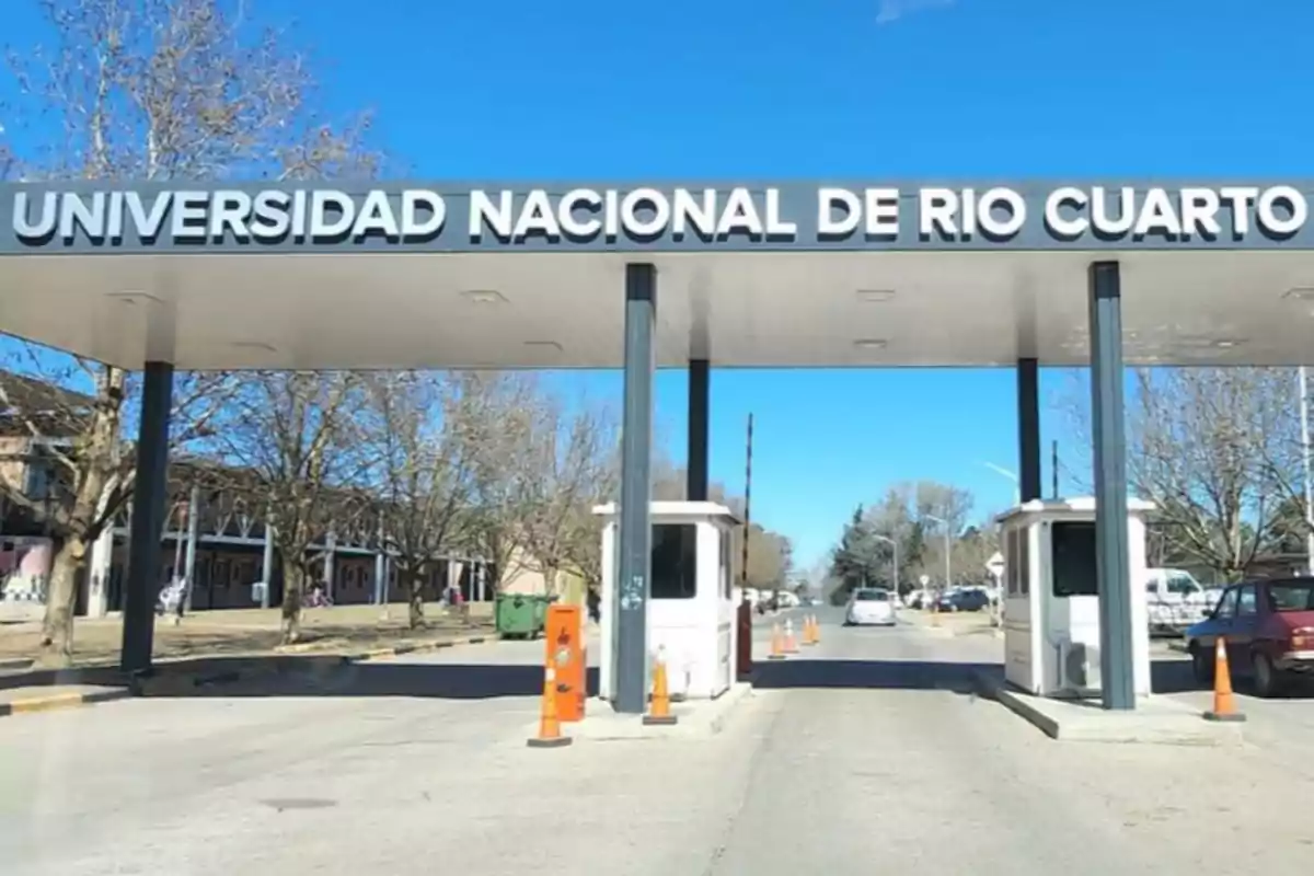 Main entrance of the National University of Río Cuarto with security booths and trees on the sides on a sunny day