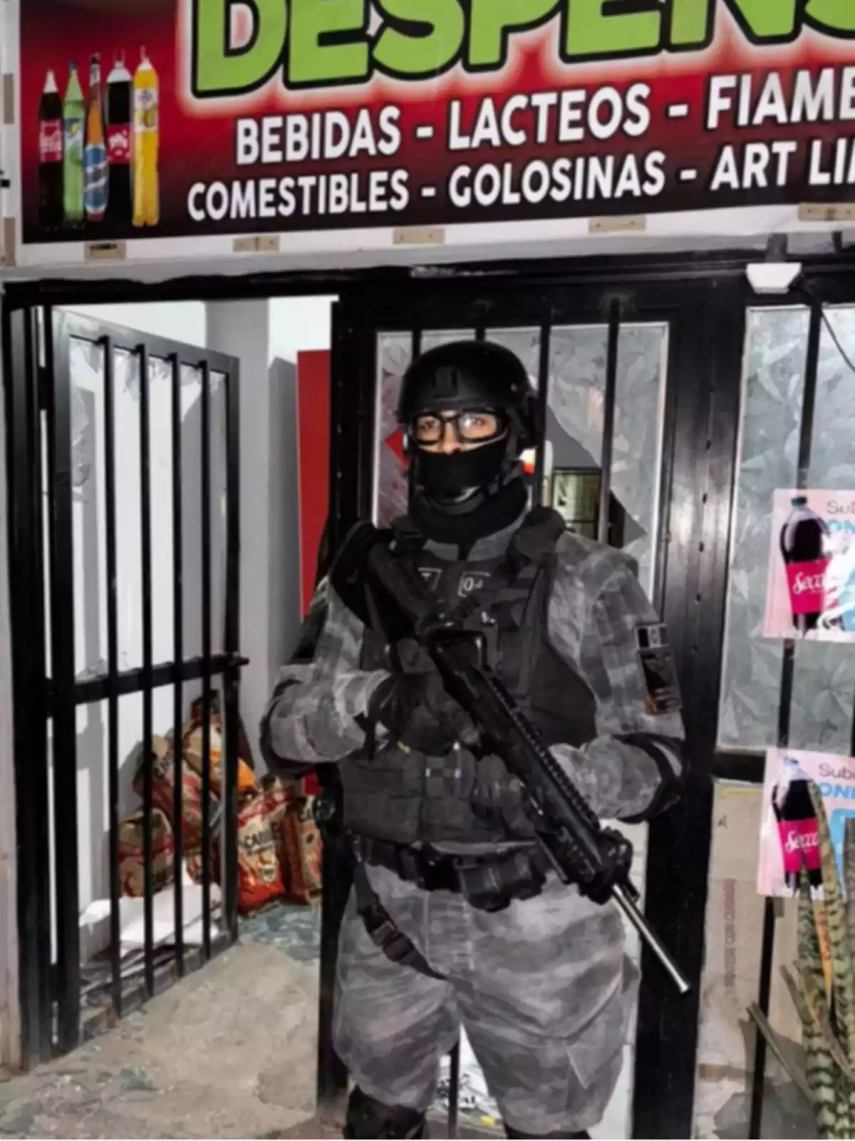 Policía fuertemente armado con uniforme táctico parado frente a la entrada de una tienda de abarrotes
