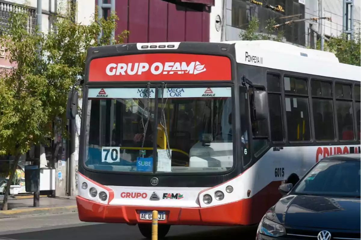 A bus from line 70 driving down a city street next to a black car