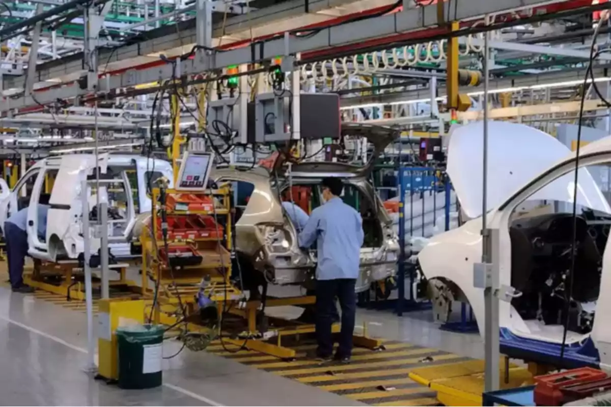 Workers assembling automobiles on a production line inside an industrial factory