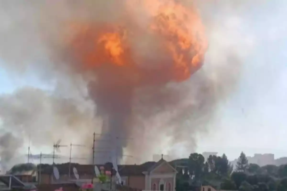 Large-scale explosion with a cloud of fire and smoke rising over an urban area Large-scale explosion with a cloud of fire and smoke rising over an urban area