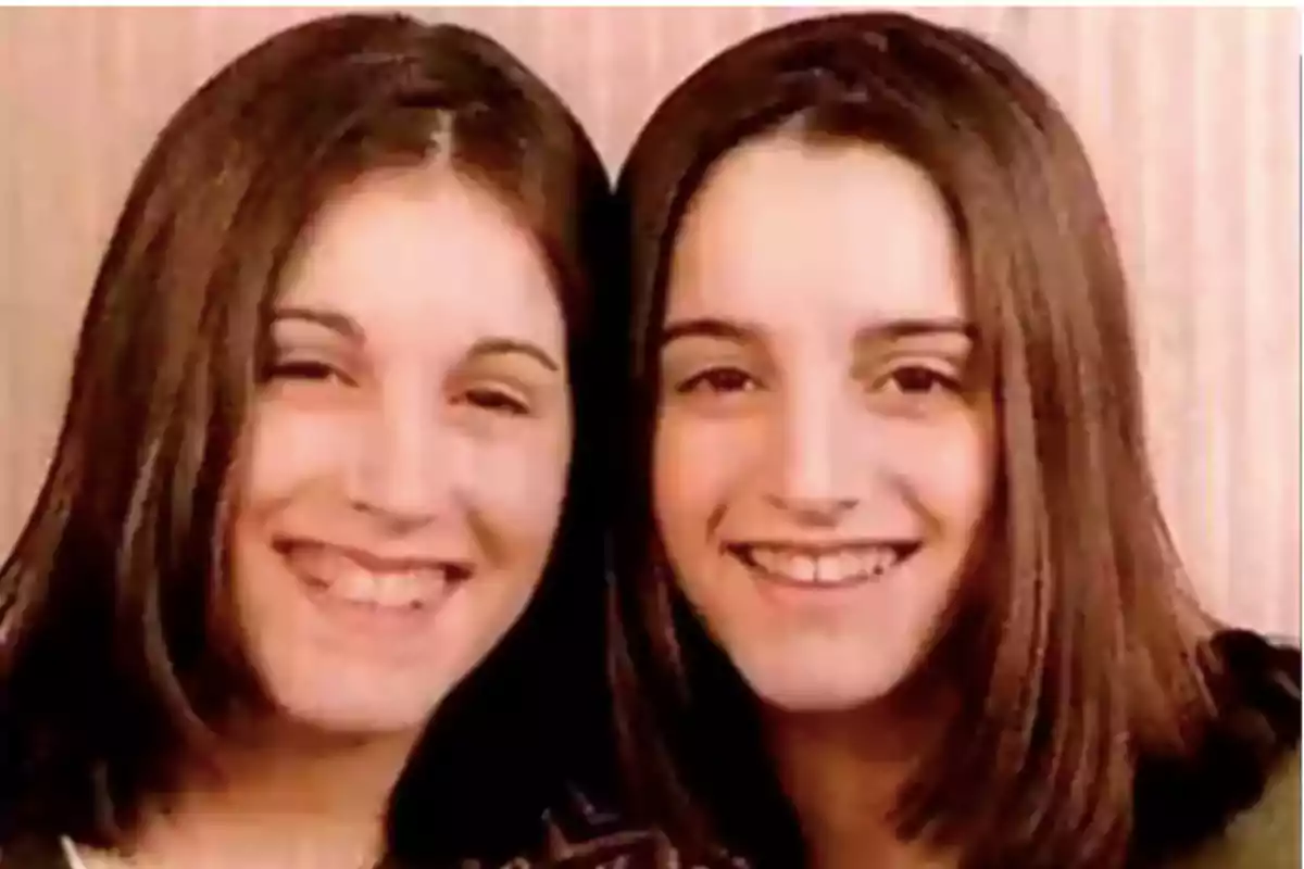 Two young girls with straight, dark hair smile together in front of a light-colored wall. Two young girls with straight, dark hair smile together in front of a light-colored wall.