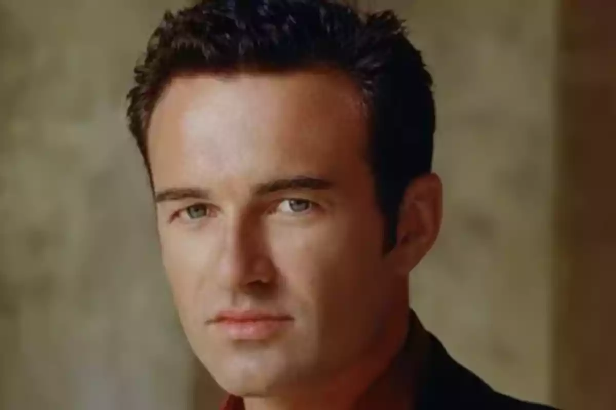 Dark-haired man with light eyes looking straight ahead with a serious expression Dark-haired man with light eyes looking straight ahead with a serious expression