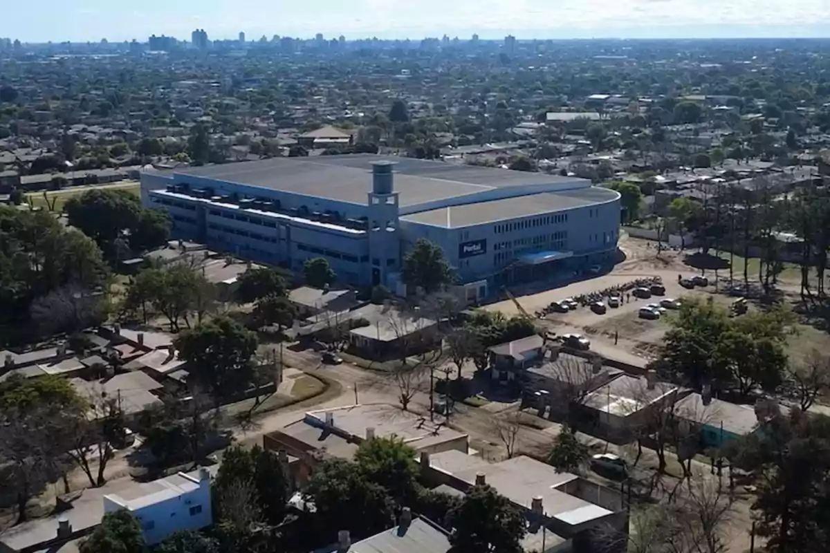 Vista aérea de un gran edificio moderno rodeado de casas y árboles en una zona urbana Vista aérea de un gran edificio moderno rodeado de casas y árboles en una zona urbana