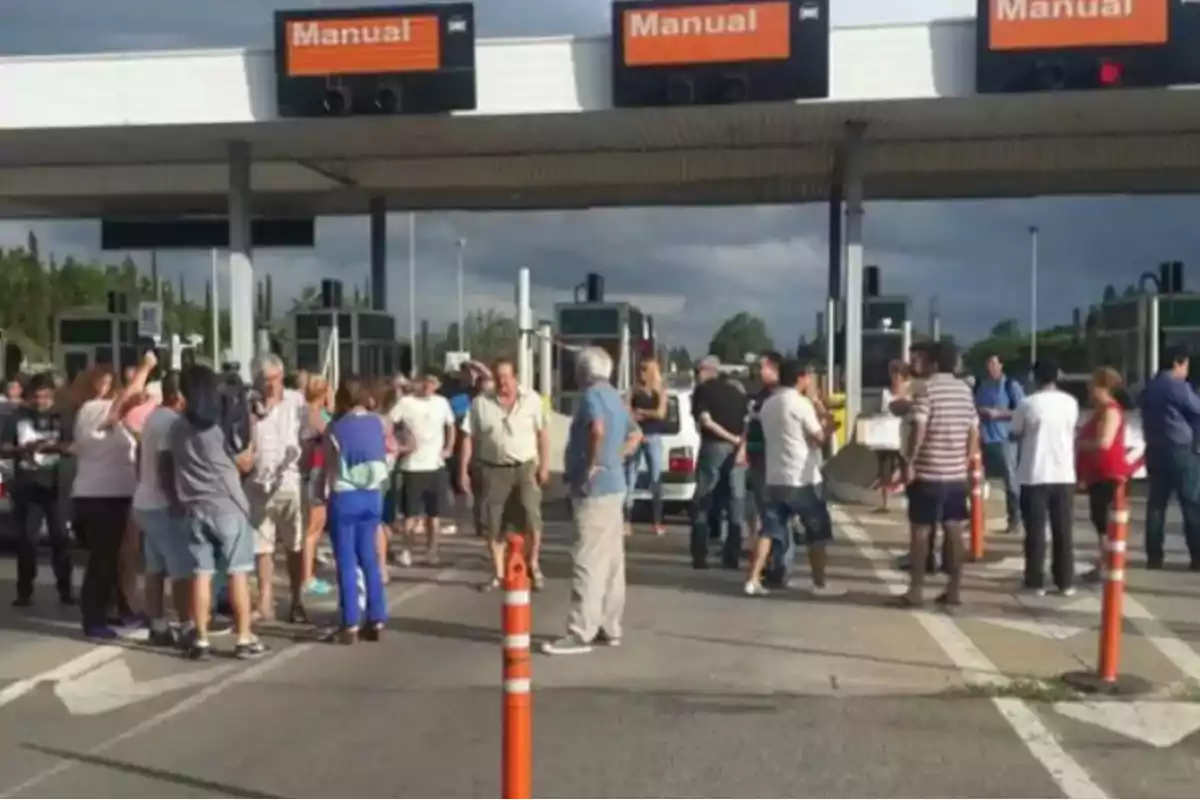 Un grupo de personas bloquea una cabina de peaje bajo un cielo nublado Un grupo de personas bloquea una cabina de peaje bajo un cielo nublado