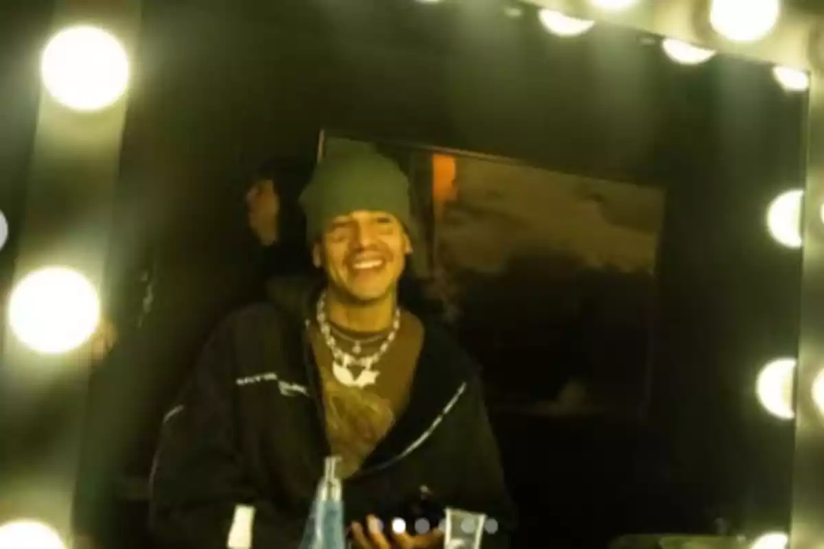 Person smiling in front of a mirror surrounded by lights in a locker room Person smiling in front of a mirror surrounded by lights in a locker room