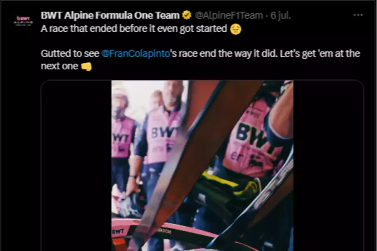 Alpine team mechanics wearing pink vests watch a single-seater in the pit lane during a motorsport race. Alpine team mechanics wearing pink vests watch a single-seater in the pit lane during a motorsport race.