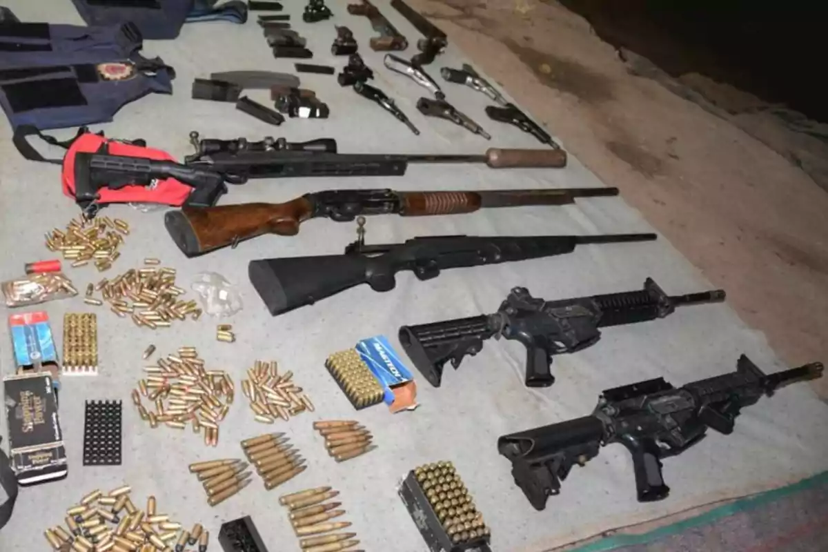Armas largas y cortas, municiones y chalecos antibalas organizados sobre una manta