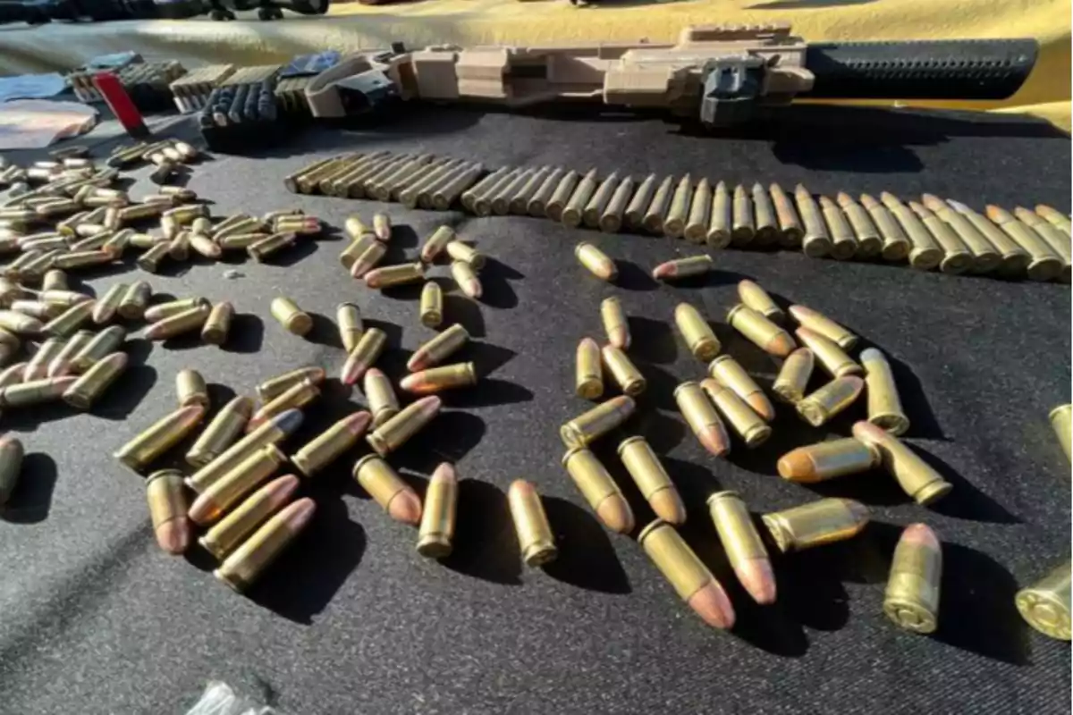 Ammunition cartridges scattered on a black surface with a long gun in the background Ammunition cartridges scattered on a black surface with a long gun in the background
