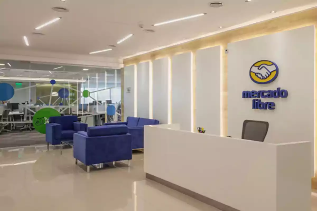 Recepción moderna de oficina de Mercado Libre con sillones azules y un escritorio blanco Recepción moderna de oficina de Mercado Libre con sillones azules y un escritorio blanco