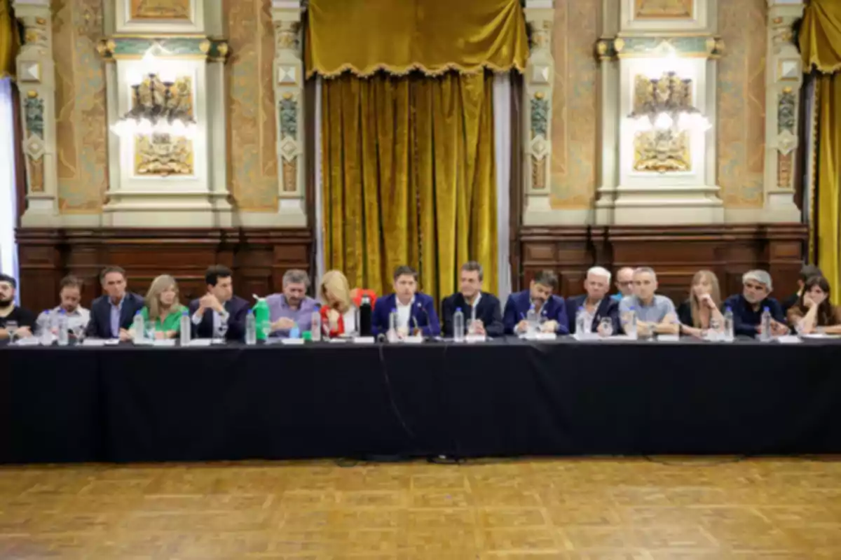 Un grupo de personas sentadas en una mesa larga en una sala elegante con cortinas doradas y paredes decoradas Un grupo de personas sentadas en una mesa larga en una sala elegante con cortinas doradas y paredes decoradas