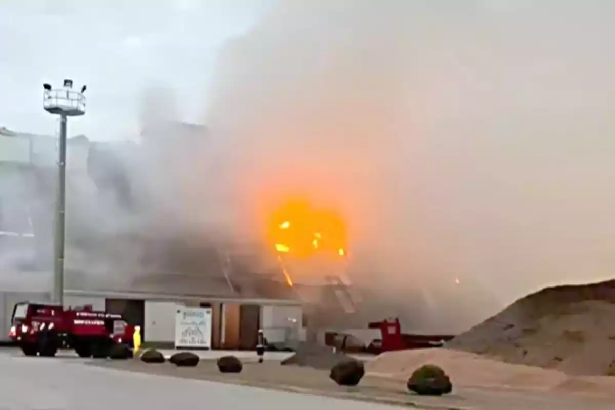 Incendio en un edificio industrial con humo denso y un camión de bomberos en el lugar Incendio en un edificio industrial con humo denso y un camión de bomberos en el lugar