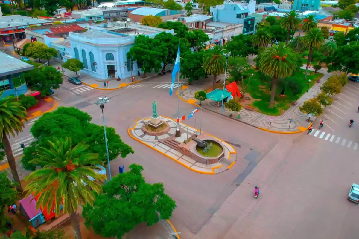 Aerial view of a central square with a fountain, a statue, flags, and trees, surrounded by buildings and streets in a city Aerial view of a central square with a fountain, a statue, flags, and trees, surrounded by buildings and streets in a city