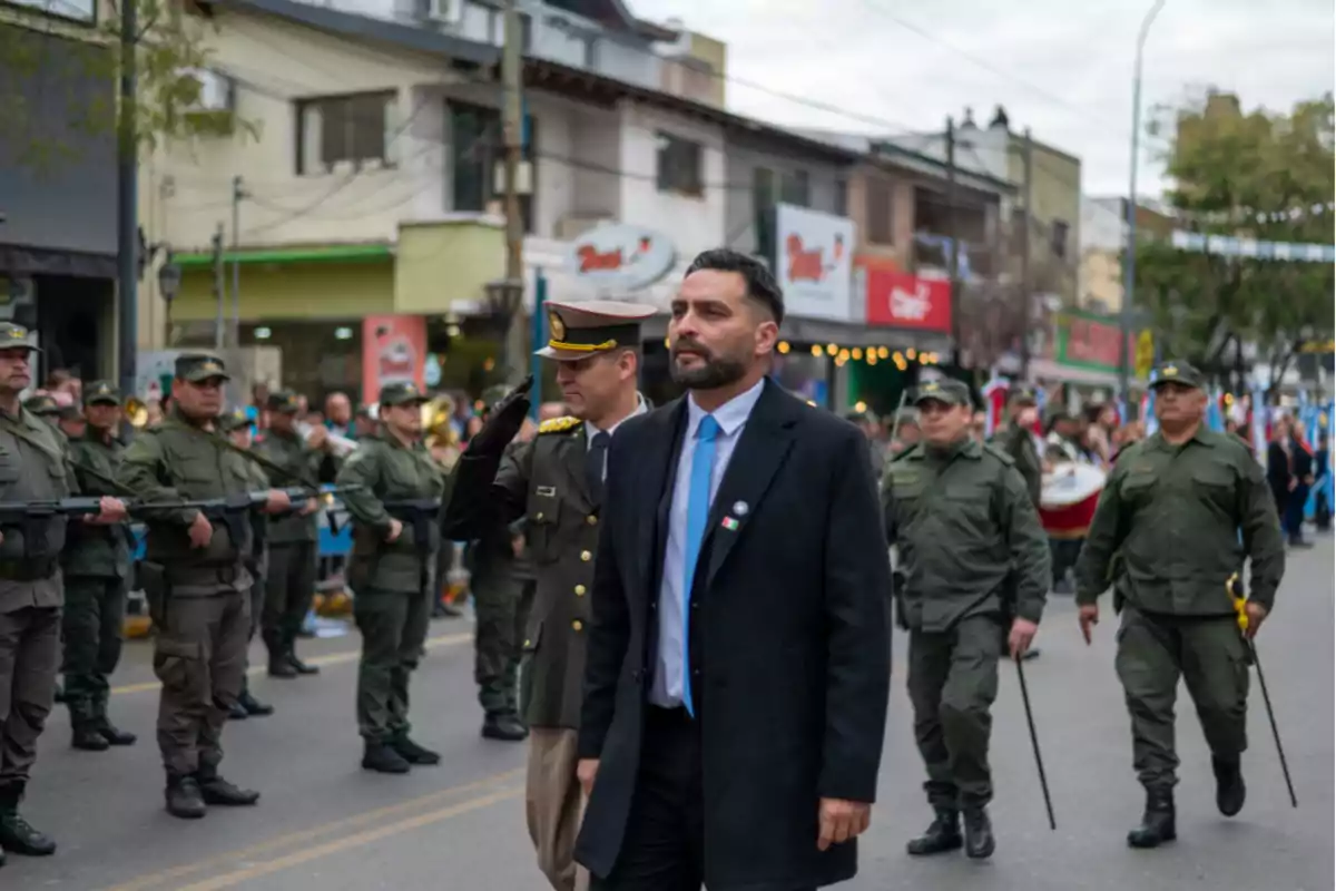 Military parade on a street with uniformed soldiers and a man in a suit walking in front