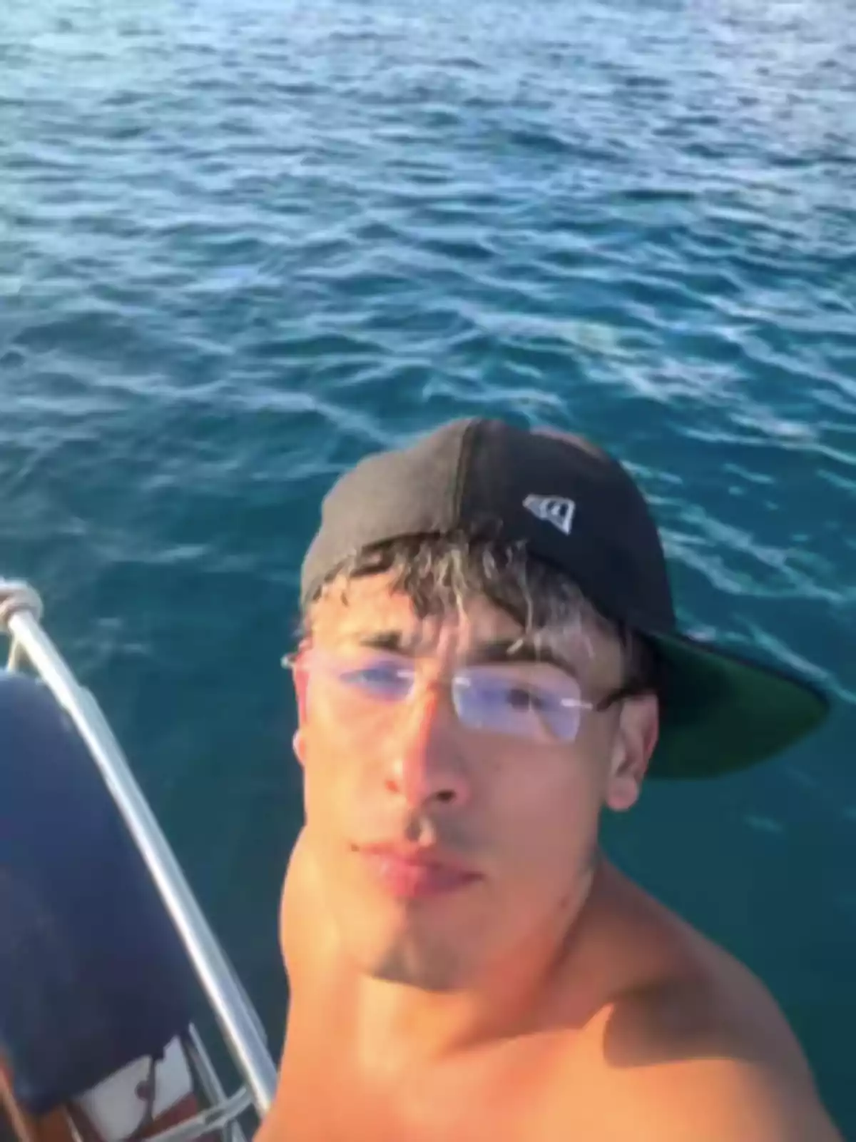 Young man with a cap and glasses taking a selfie on a boat on the sea Young man with a cap and glasses taking a selfie on a boat on the sea