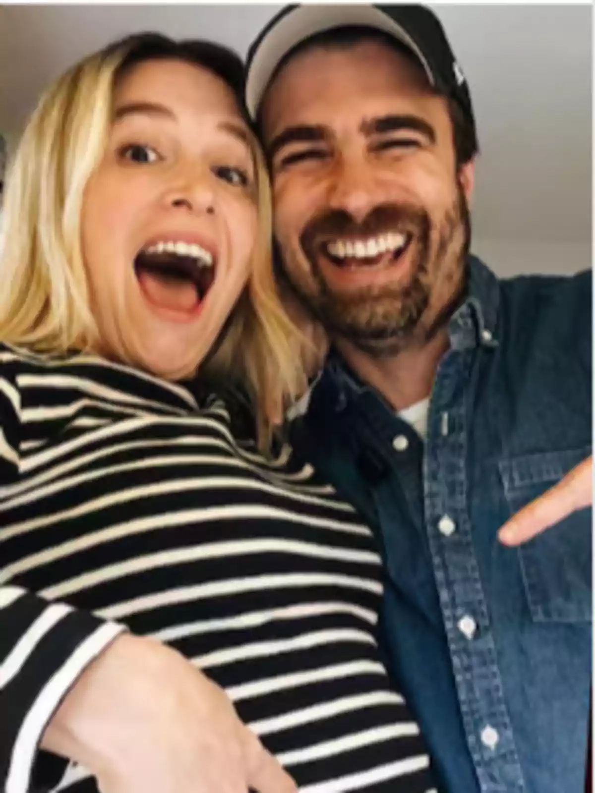 Smiling couple posing together while the pregnant woman wears a black and white striped jersey Smiling couple posing together while the pregnant woman wears a black and white striped jersey