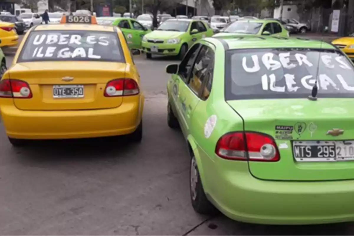 Yellow and green taxis with messages in the rear windows saying Uber is illegal parked on the street Yellow and green taxis with messages in the rear windows saying Uber is illegal parked on the street